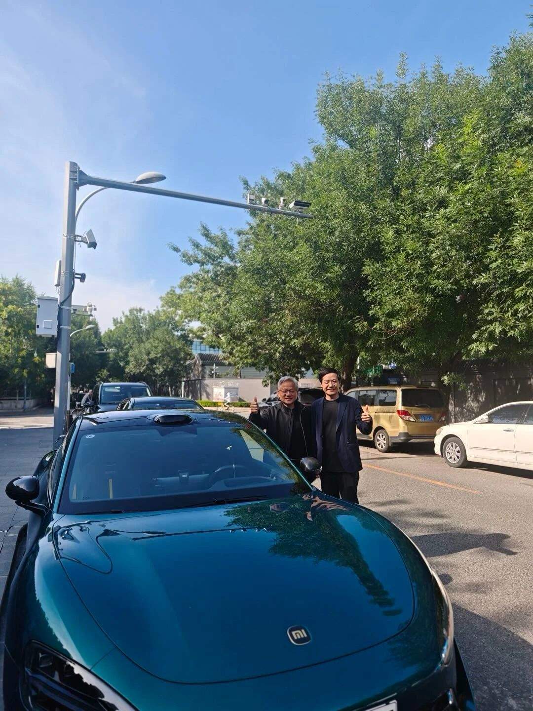 黄仁勋与雷军合影,35度天气仍穿皮衣!两人站在一辆小米汽车前,面带微笑,显得十分亲切